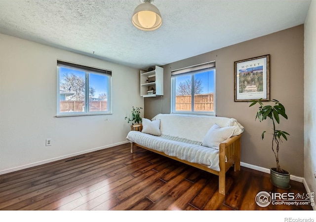 living area with a textured ceiling, baseboards, hardwood / wood-style flooring, and a healthy amount of sunlight