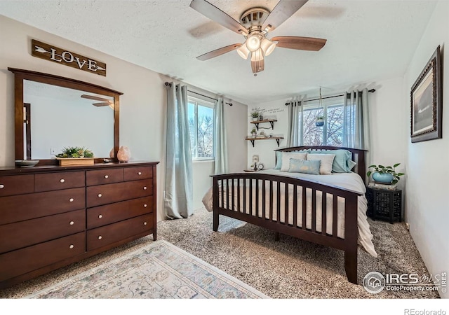 bedroom with a textured ceiling, multiple windows, a ceiling fan, and light colored carpet