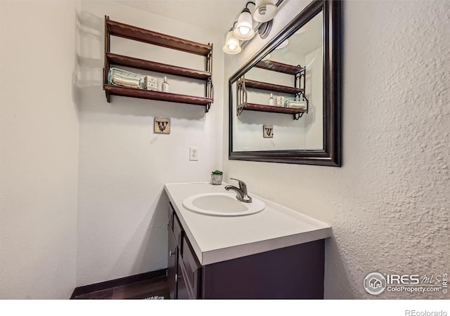 bathroom featuring a textured wall, vanity, and baseboards