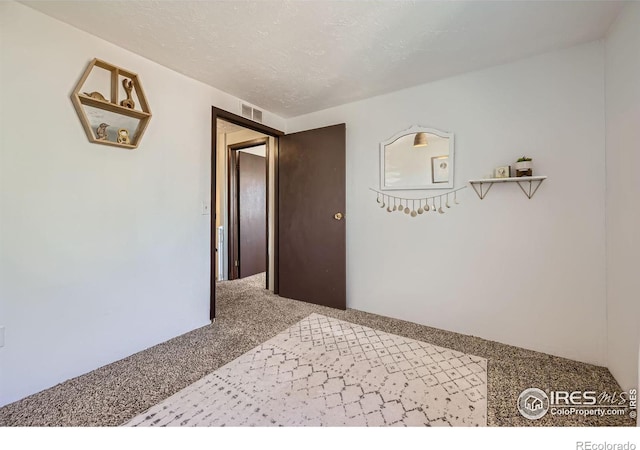 hall featuring a textured ceiling, carpet, and visible vents