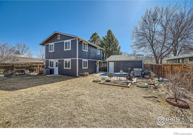 rear view of house with a yard, a fenced backyard, central AC unit, and an outdoor structure