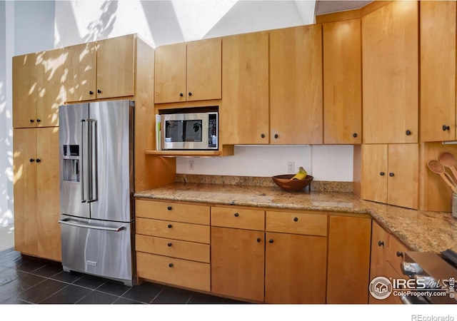 kitchen featuring stainless steel appliances, dark tile patterned flooring, and light stone countertops