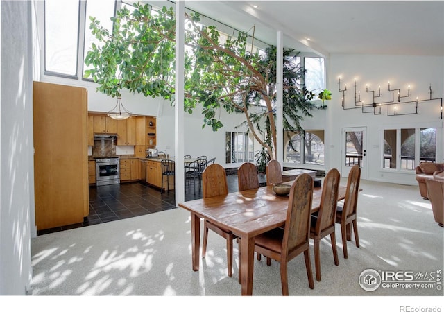 dining room with a towering ceiling, dark carpet, and dark tile patterned flooring