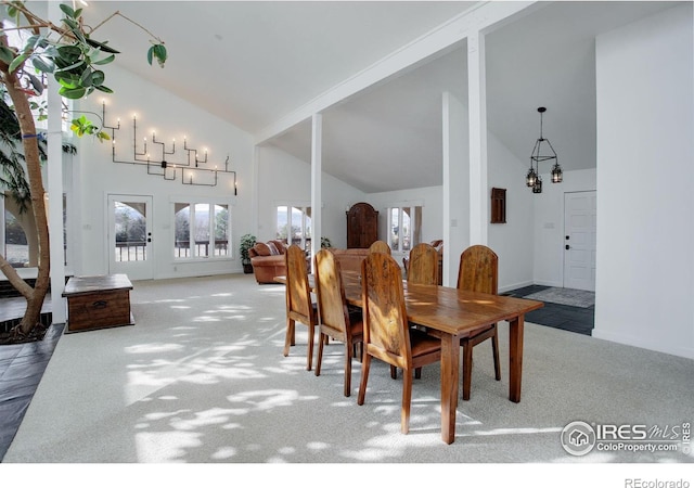 carpeted dining room featuring high vaulted ceiling