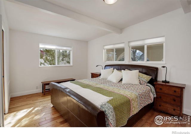 bedroom featuring wood-type flooring, baseboards, and beam ceiling