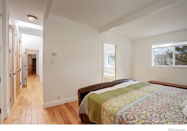 bedroom featuring light wood-style floors, baseboards, and beamed ceiling