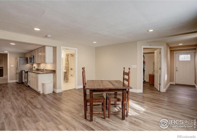 dining space featuring baseboards, a textured ceiling, recessed lighting, and light wood-style floors