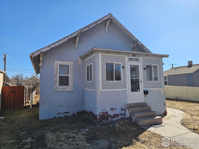 view of front of property with entry steps, fence, and stucco siding