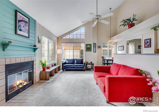 carpeted living room with high vaulted ceiling, a tile fireplace, and a ceiling fan