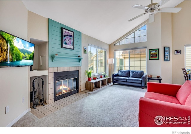 living room with ceiling fan, high vaulted ceiling, carpet, baseboards, and a tiled fireplace