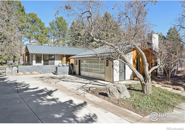 view of front of property with a garage, a standing seam roof, metal roof, and concrete driveway