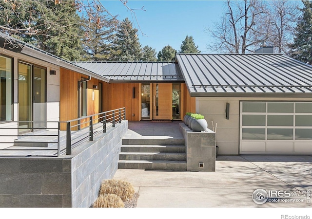 view of front facade with driveway, a standing seam roof, and metal roof