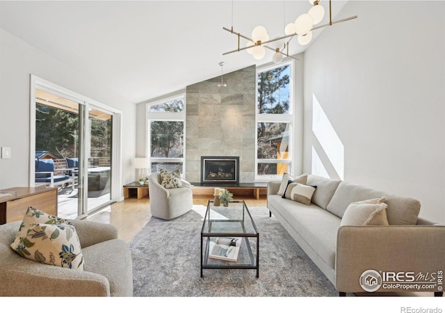 living area featuring high vaulted ceiling, a tile fireplace, plenty of natural light, and wood finished floors