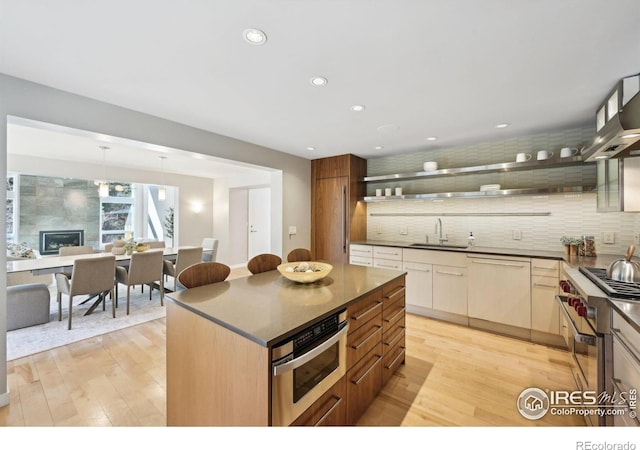 kitchen featuring stainless steel appliances, backsplash, open shelves, and light wood-style flooring