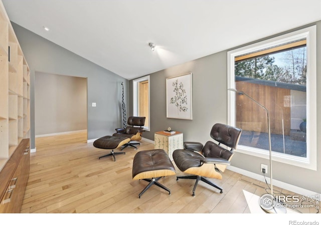 sitting room featuring lofted ceiling, baseboards, visible vents, and light wood finished floors