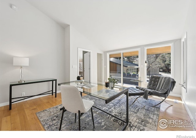 dining area featuring baseboards, vaulted ceiling, and wood finished floors