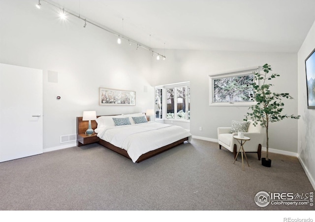 carpeted bedroom featuring high vaulted ceiling, rail lighting, visible vents, and baseboards