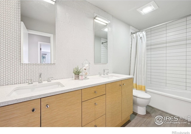 bathroom featuring wood finished floors, a sink, toilet, and double vanity