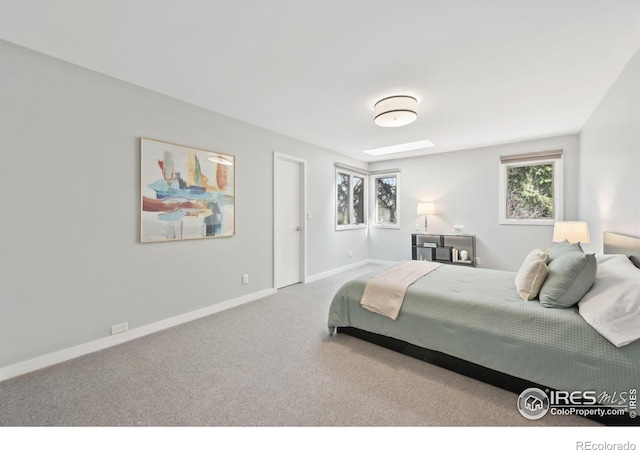 carpeted bedroom with a skylight and baseboards