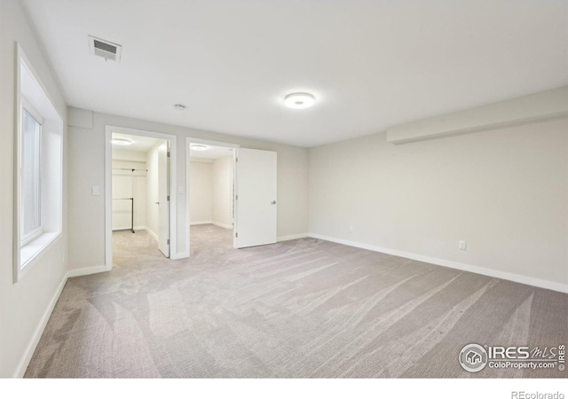 unfurnished bedroom featuring carpet floors, baseboards, visible vents, and a walk in closet