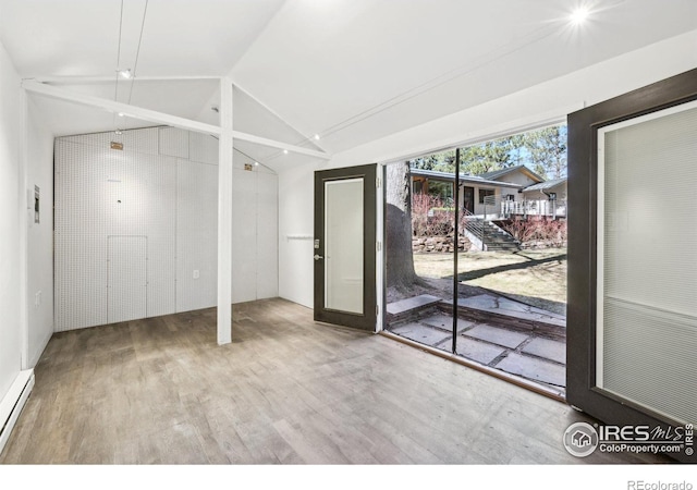 interior space with a baseboard heating unit, vaulted ceiling, and wood finished floors