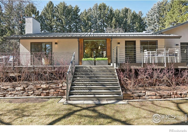 mid-century inspired home with metal roof, covered porch, stairway, stucco siding, and a standing seam roof