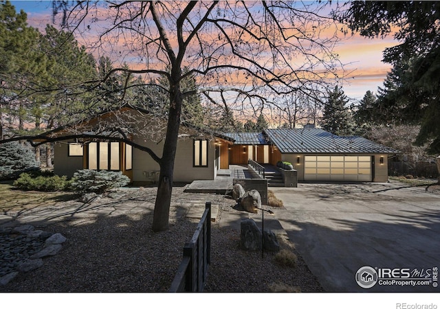 view of front of house featuring a garage, metal roof, a standing seam roof, and concrete driveway