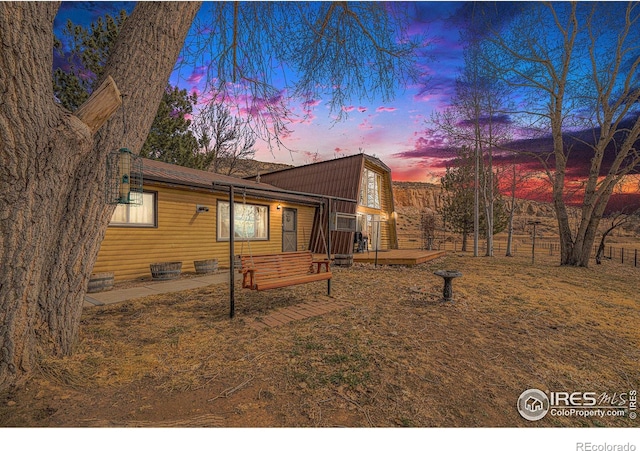 back of property at dusk with a wooden deck