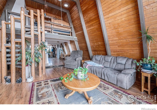 unfurnished living room featuring wooden ceiling, beamed ceiling, wood finished floors, wood walls, and high vaulted ceiling