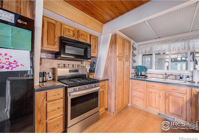 kitchen with stainless steel range with gas cooktop, light wood finished floors, visible vents, a sink, and black microwave