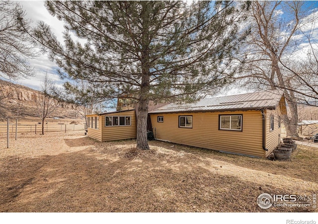 back of house with metal roof, log veneer siding, and fence