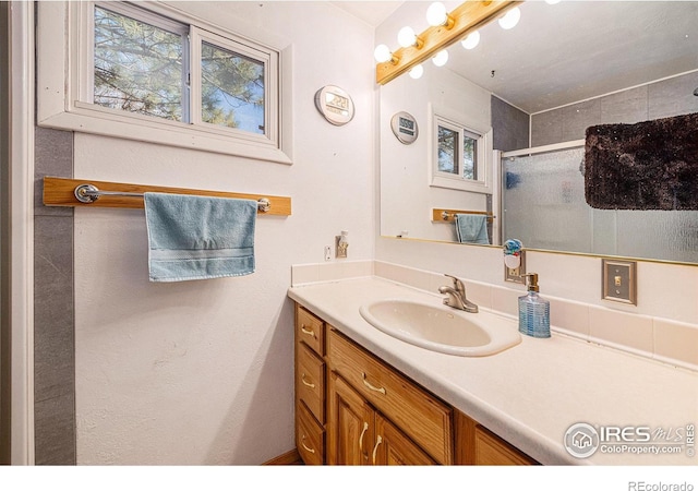 bathroom with a wealth of natural light, a shower stall, and vanity