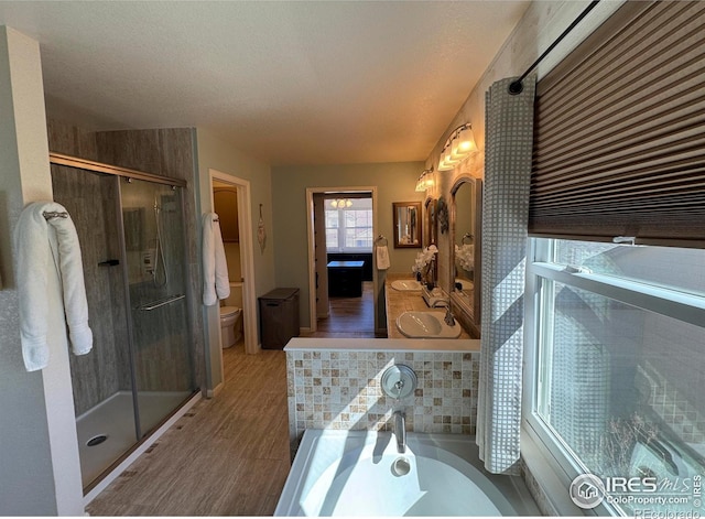 full bathroom featuring a stall shower, toilet, wood finished floors, and a garden tub