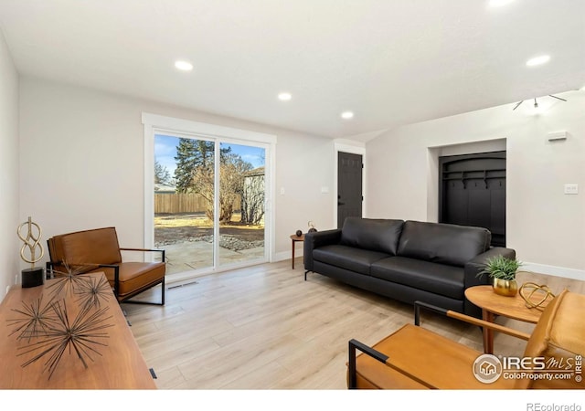 living room featuring light wood-style flooring, visible vents, baseboards, and recessed lighting