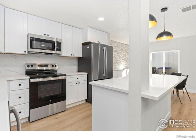 kitchen with stainless steel appliances, light wood-type flooring, white cabinets, and visible vents