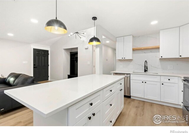 kitchen featuring decorative backsplash, a sink, light countertops, light wood-style floors, and stainless steel dishwasher