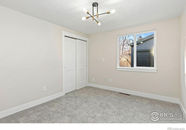 unfurnished bedroom featuring carpet, visible vents, baseboards, and an inviting chandelier