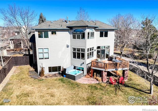 back of house with a deck, a patio, a fenced backyard, a lawn, and a hot tub