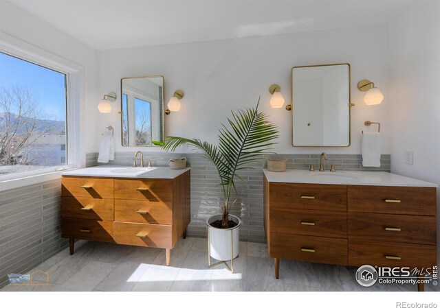 bathroom with two vanities, a sink, and tile walls