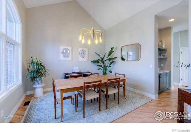 dining space with light wood-type flooring, baseboards, visible vents, and a notable chandelier