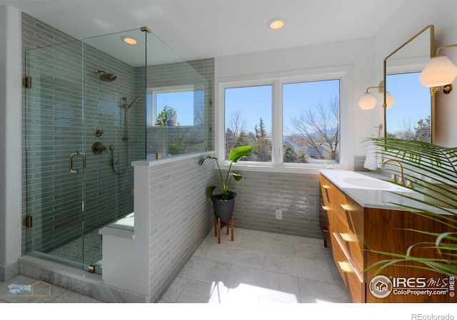 bathroom with a stall shower, recessed lighting, tile walls, and vanity