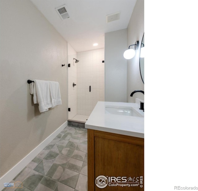 bathroom with vanity, a shower stall, visible vents, and baseboards