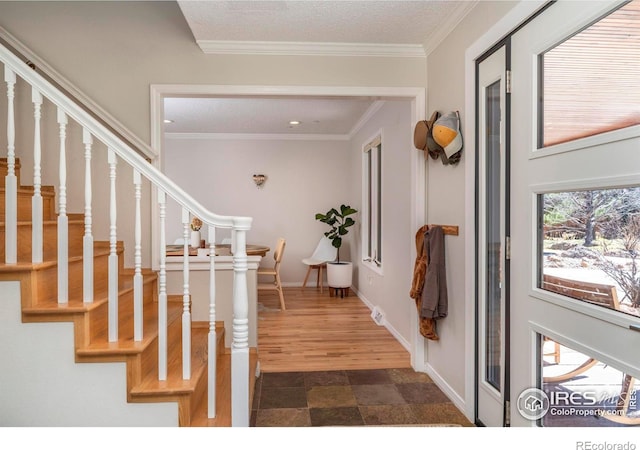 foyer featuring a textured ceiling, ornamental molding, stairway, and baseboards