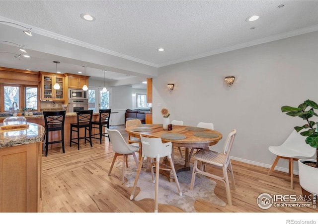 dining space with crown molding, a healthy amount of sunlight, and light wood-style floors