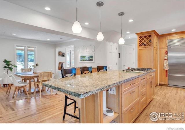 kitchen with recessed lighting, appliances with stainless steel finishes, light wood-style floors, ornamental molding, and a kitchen bar