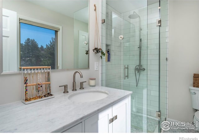 bathroom with a stall shower, vanity, and toilet