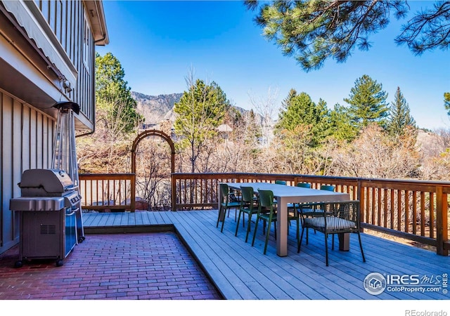 deck with outdoor dining area, grilling area, and a mountain view