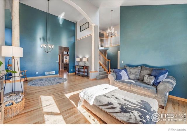 living area with a chandelier, visible vents, stairway, and wood finished floors