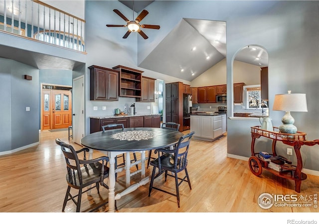 dining area featuring high vaulted ceiling, baseboards, ceiling fan, and light wood finished floors