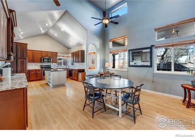 dining room featuring a ceiling fan, baseboards, high vaulted ceiling, and light wood finished floors